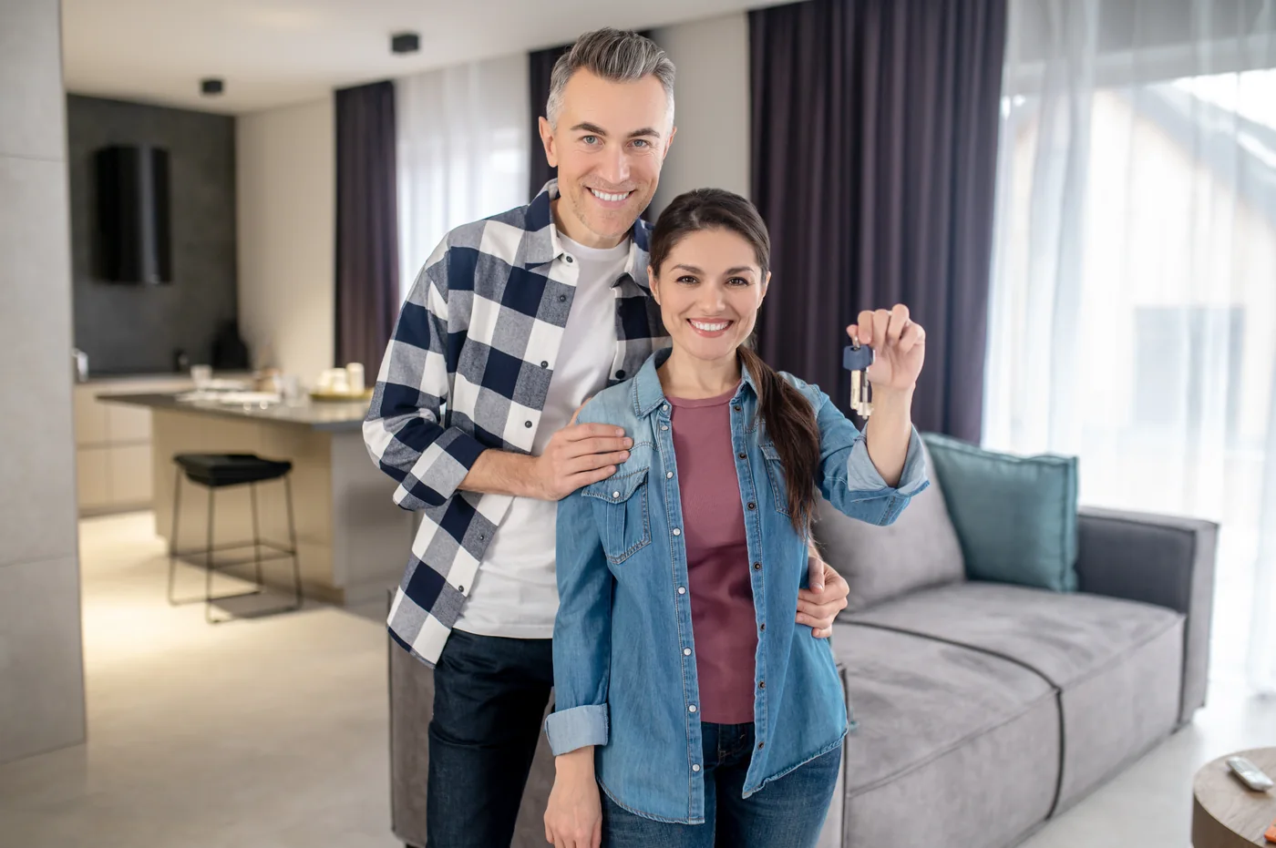 Casal segurando a chave da casa nova na sala do imóvel