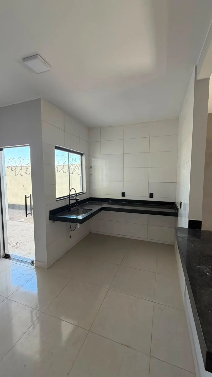 Cozinha com bancada em granito preto e janela ampla