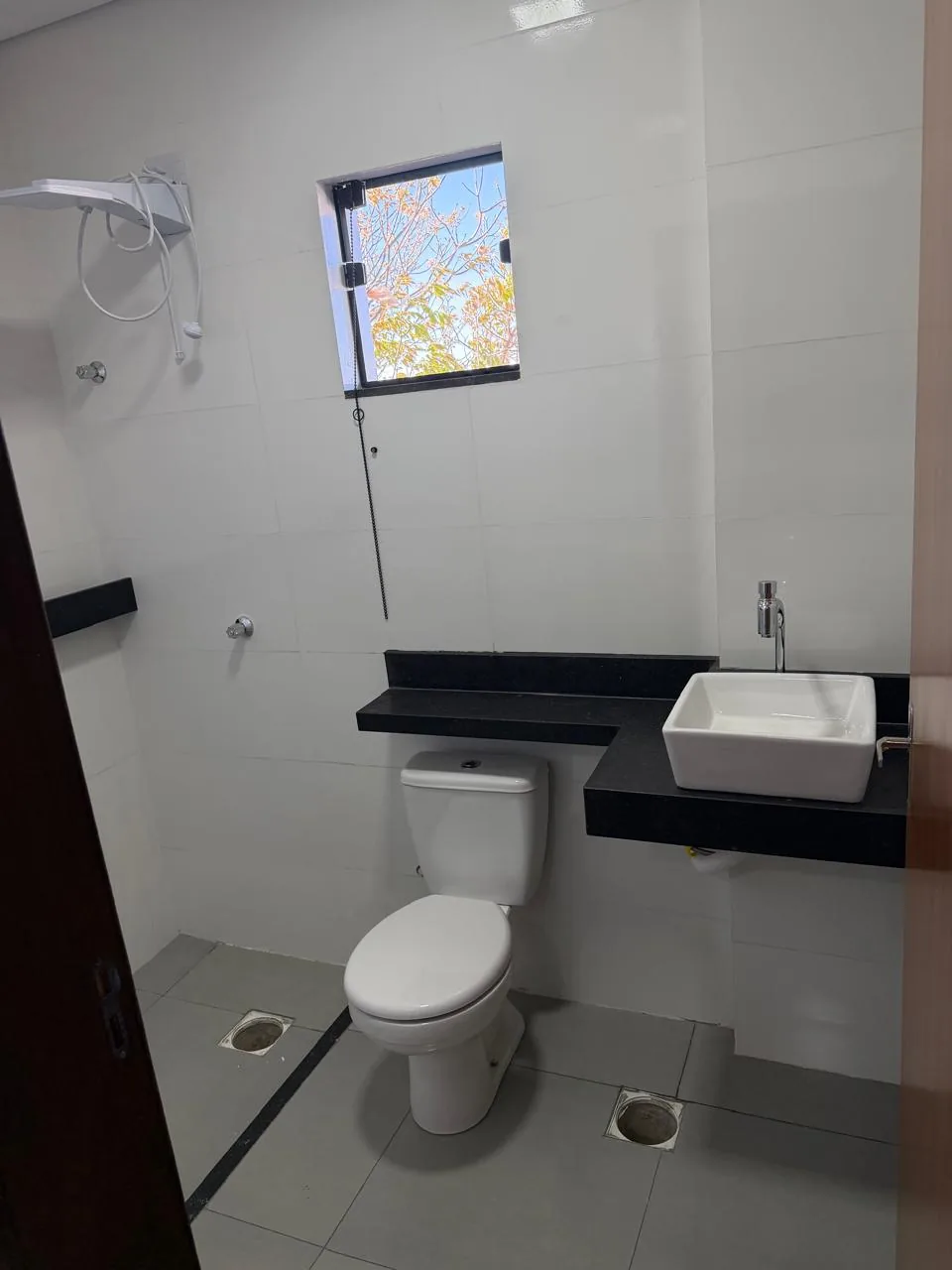 Banheiro com cuba de apoio, bancada preta e janela