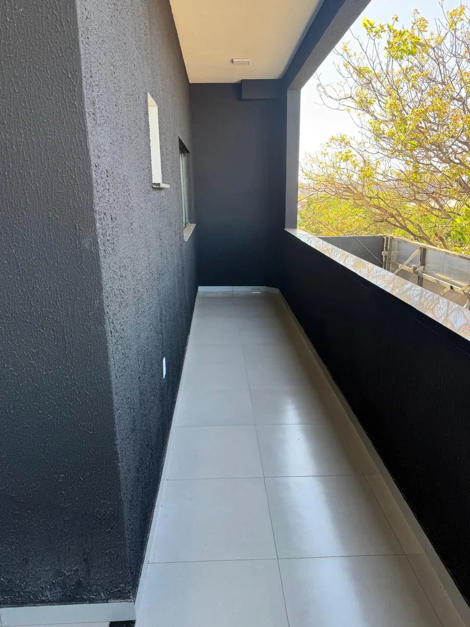 Varanda lateral com parede escura e vista para o verde