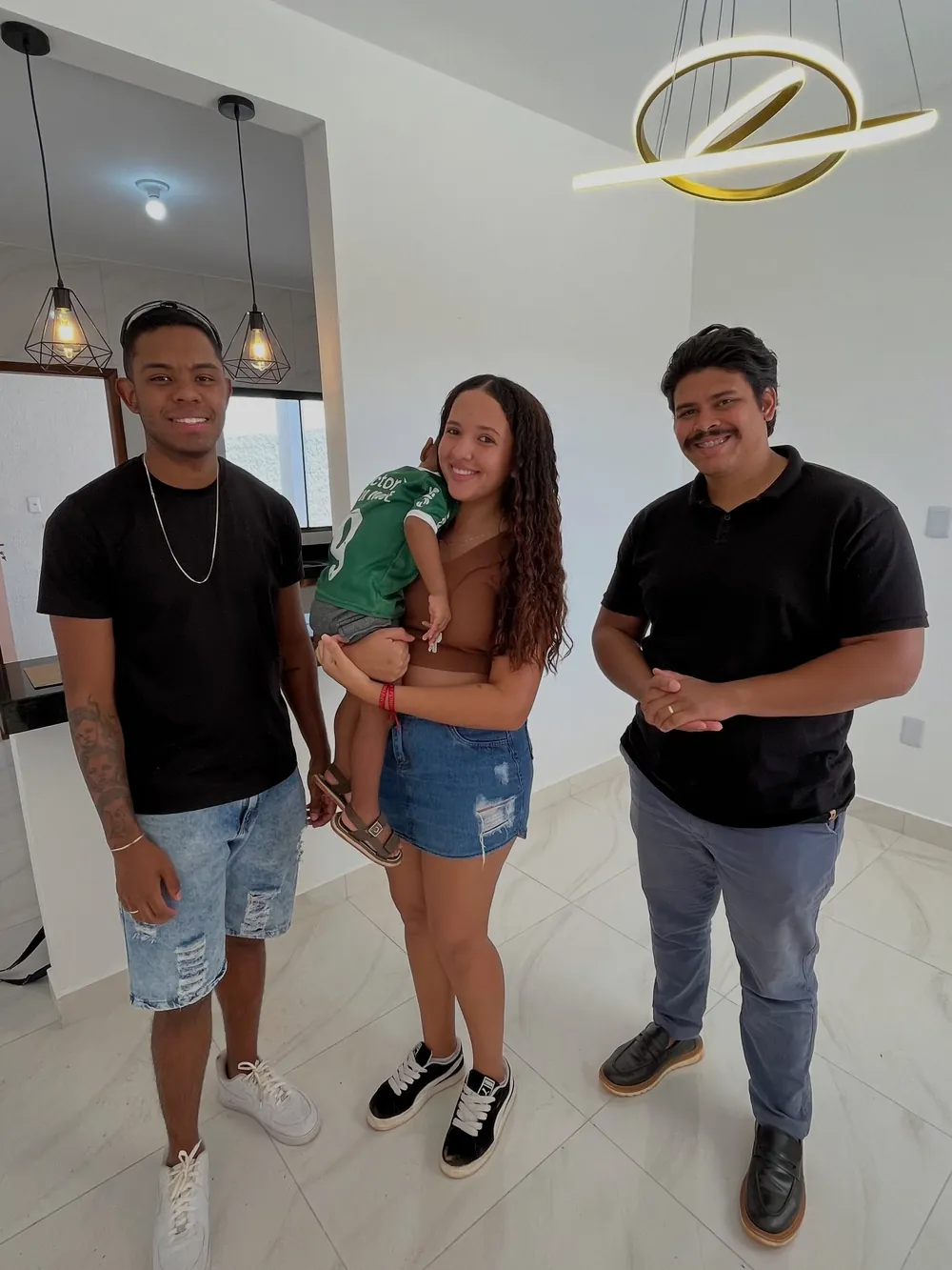 Casal com o filho no colo ao lado do corretor no dia da entrega